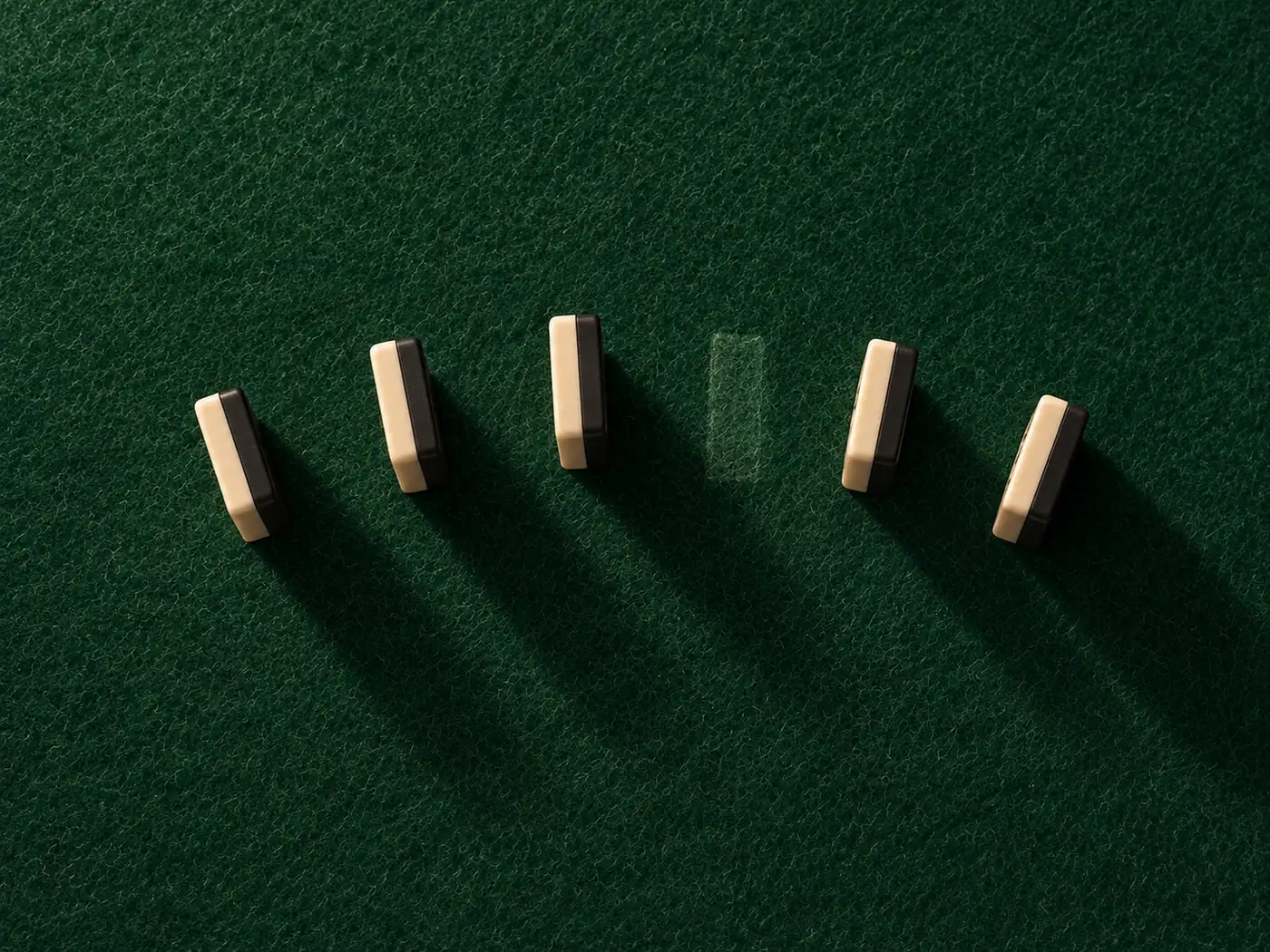 Five dominoes standing in an arc on green felt; one place in the arc is only a dust mark where a tile used to stand